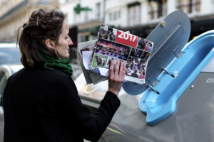 femme jetant magazines et journaux dans poubelle bleue