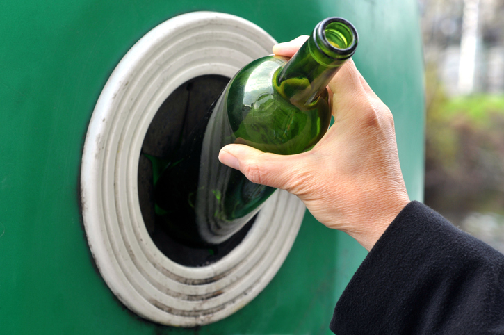 une bouteille en verre déposée dans un conteneur de tri